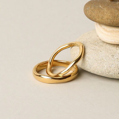 Gemini gold rings on pebbles